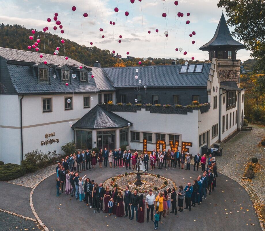 Hochzeitsgesellschaft in Herzform vor dem Schlossberg